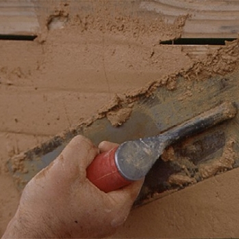 Site-made earth and lime plaster mix applied to wooden lath in modified stick-frame wall